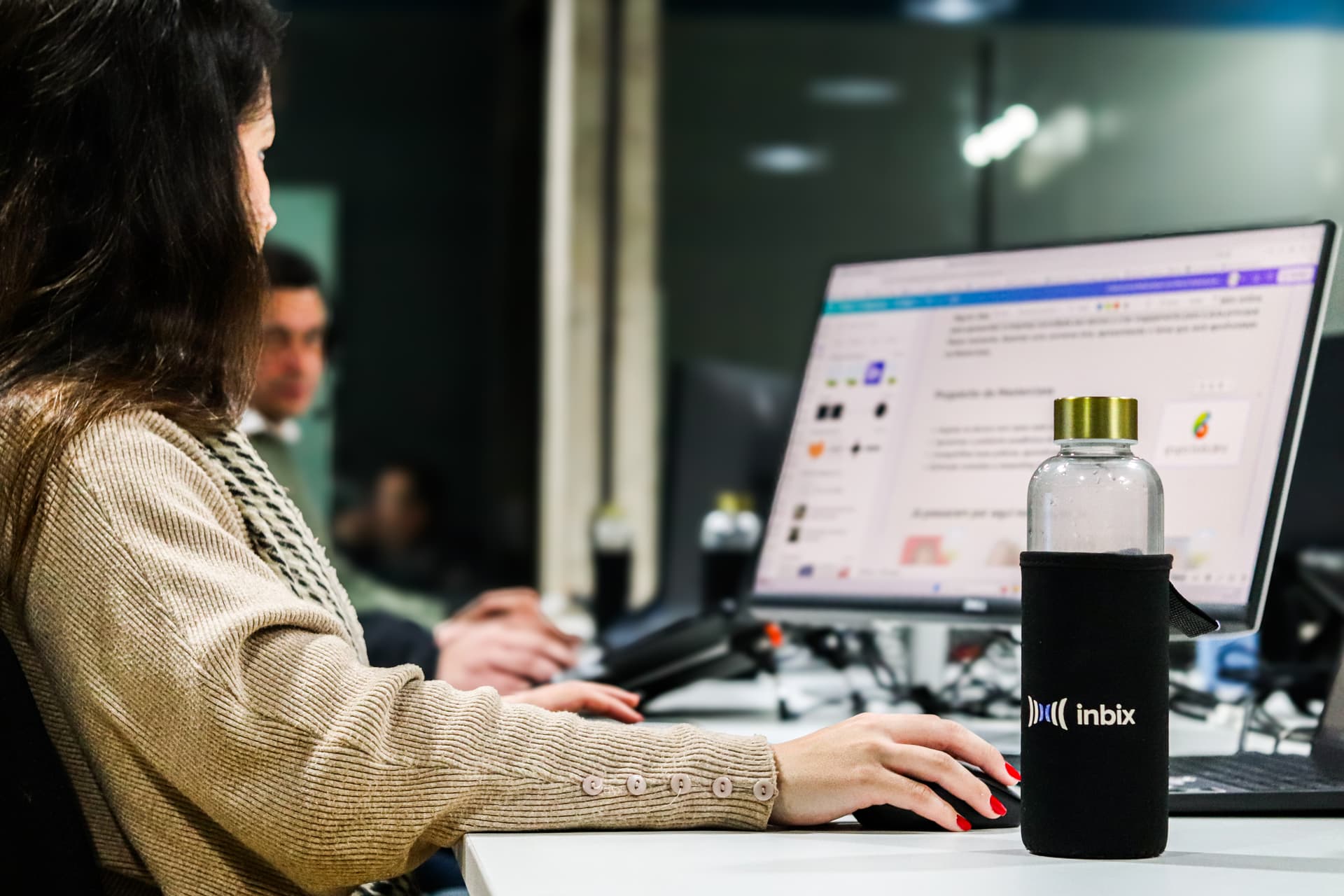 Profissional trabalhando ao computador com garrafa da Inbix em primeiro plano
