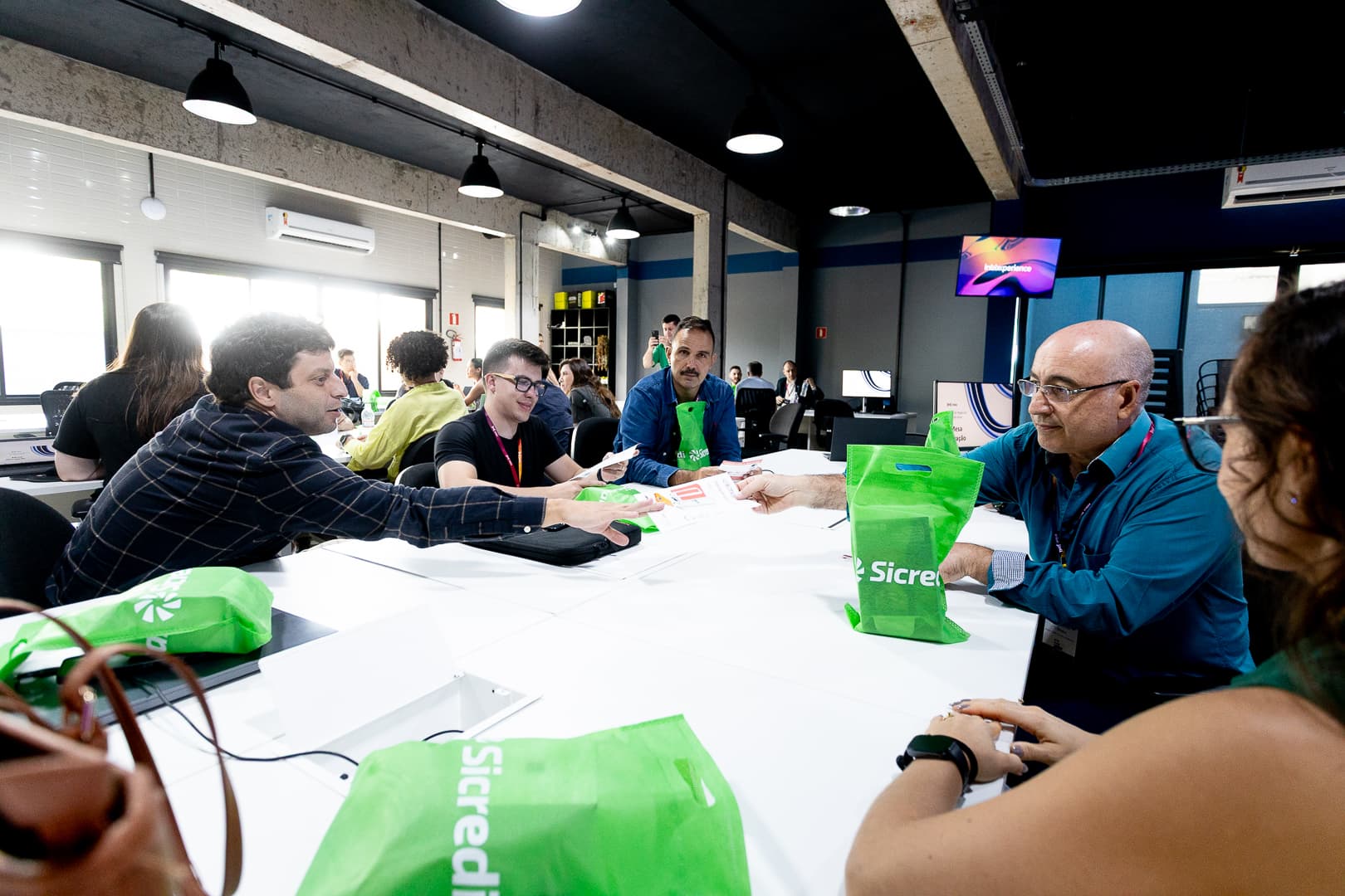 Grupo de participantes em dinâmica de trabalho ao redor de uma mesa