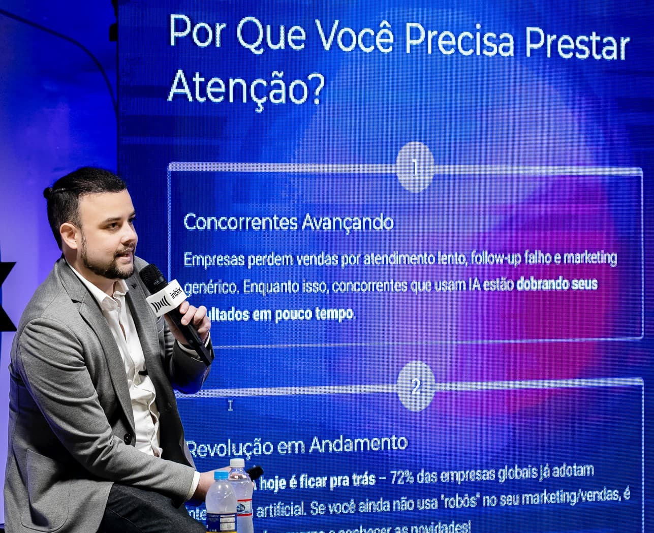 Palestrante ao lado do slide Por que você precisa prestar atenção, sobre concorrência e IA