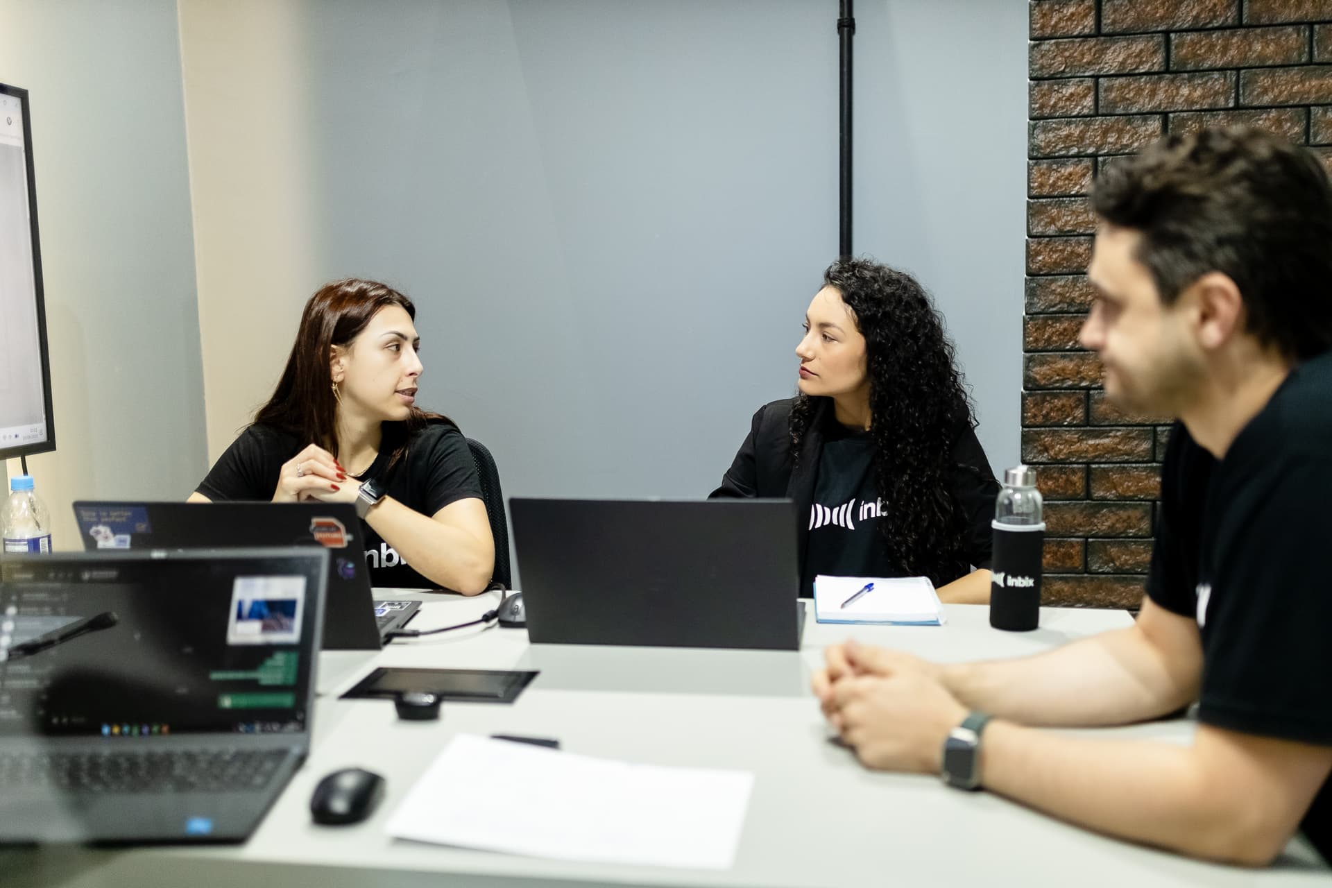 Três profissionais discutindo um projeto em reunião com notebooks