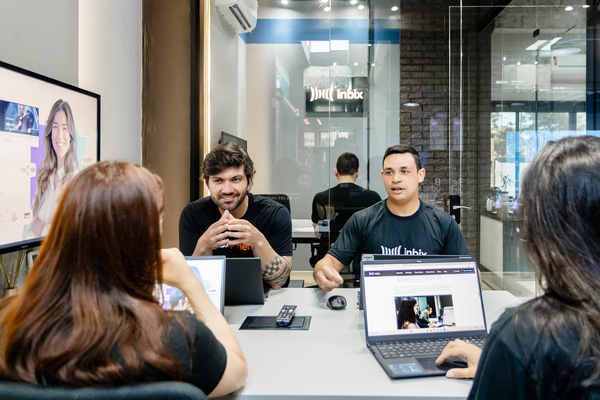 Reunião híbrida da equipe da Inbix, com uma participante remota no monitor