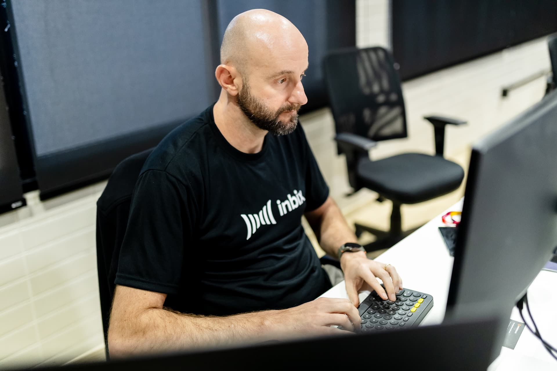 Profissional de camiseta da Inbix concentrado no trabalho ao computador