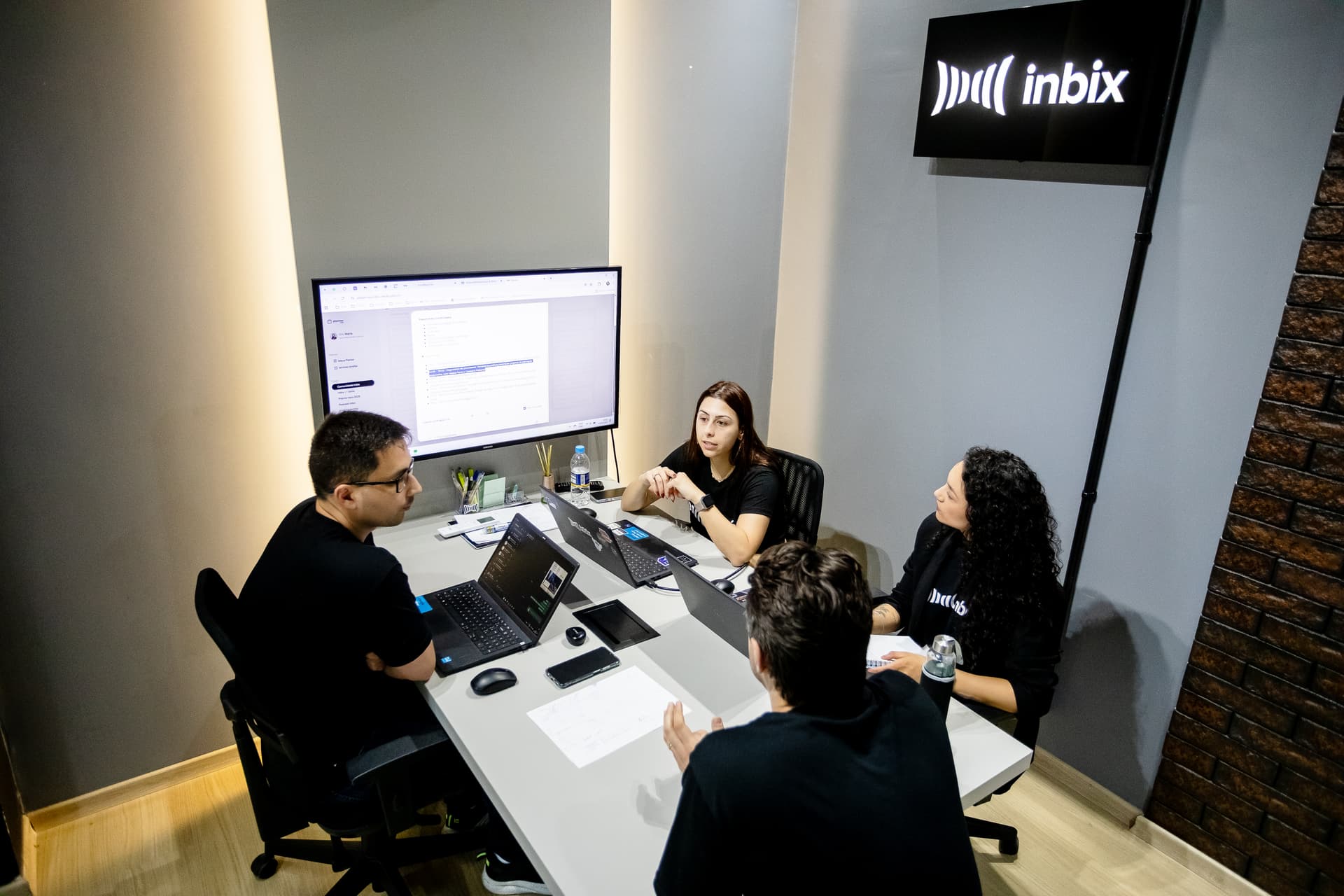 Equipe da Inbix em reunião de trabalho vista de cima, em sala com a marca na parede