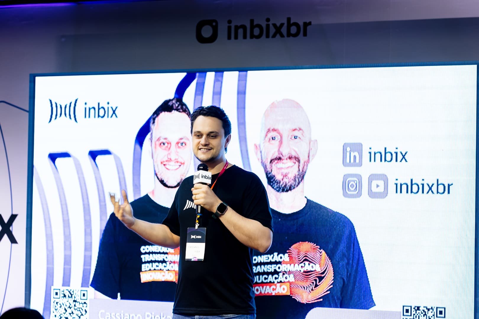 Palestrante da Inbix no palco diante do telão com os perfis da empresa nas redes sociais