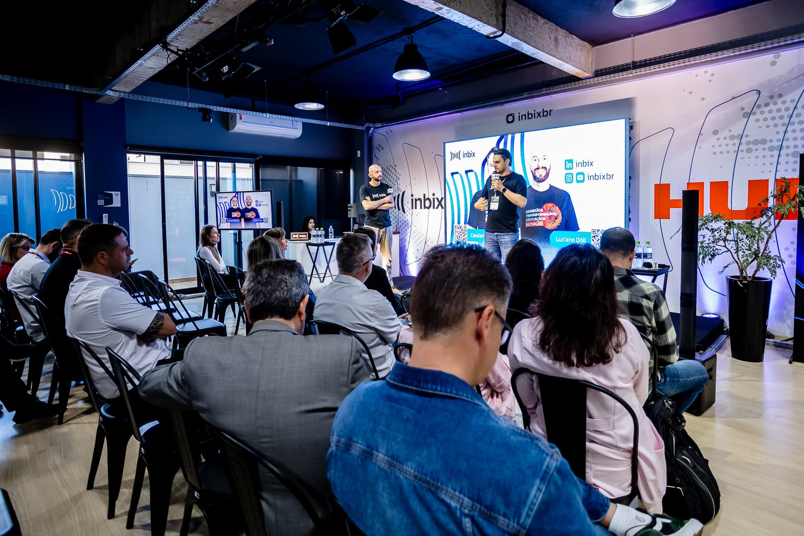 Público acompanhando a apresentação diante do telão da Inbix