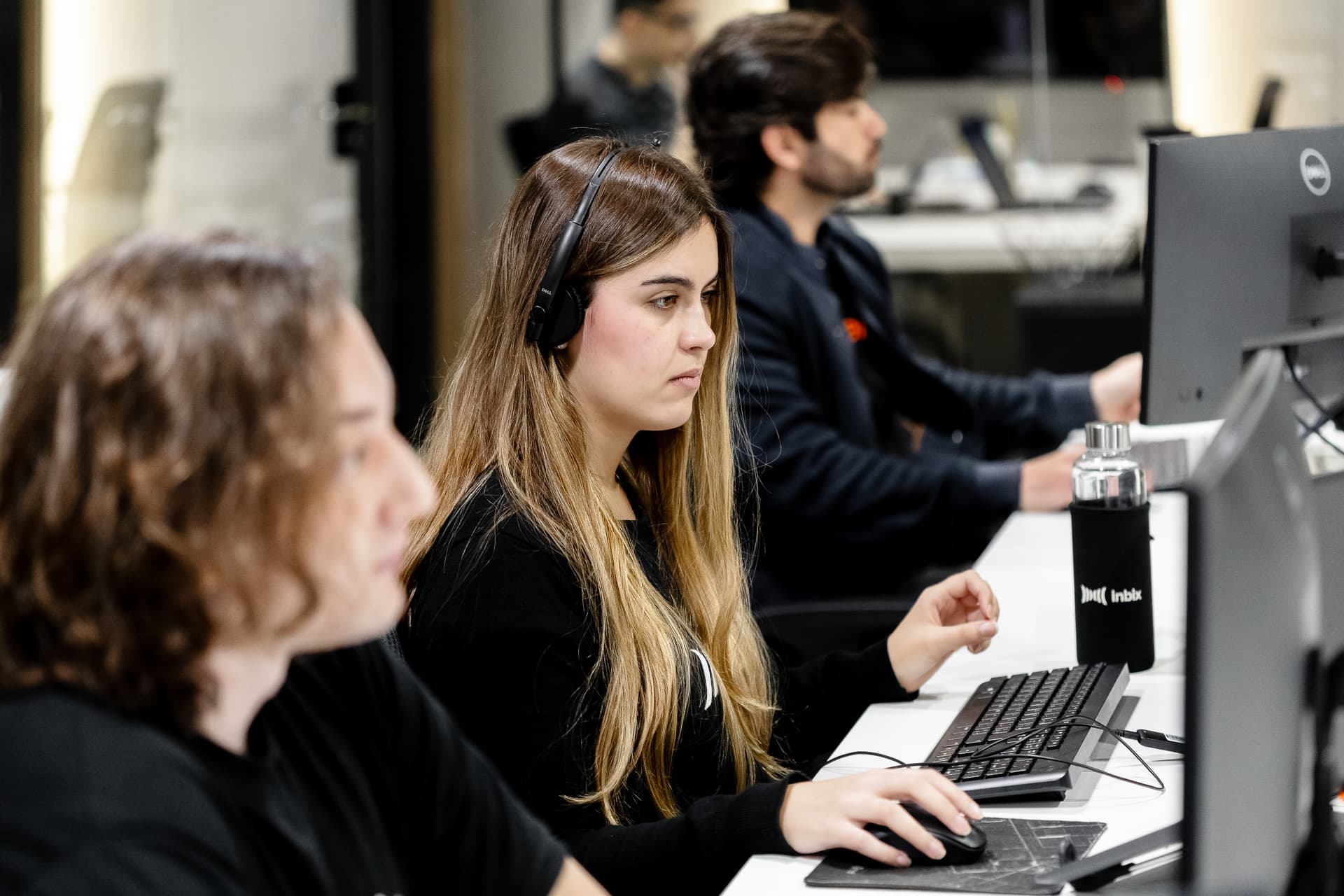 Analista de fones de ouvido trabalhando ao computador junto da equipe