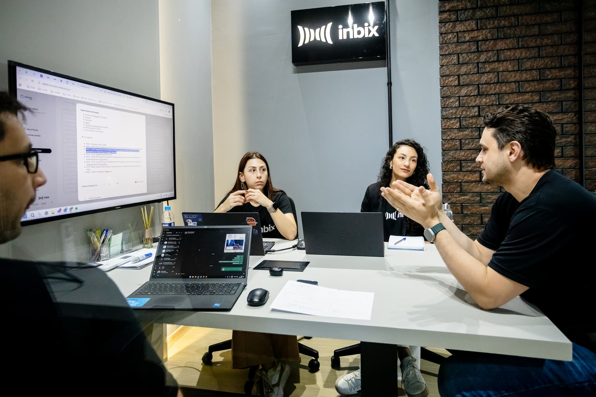 Equipe da Inbix em reunião de trabalho em sala com notebooks e monitor