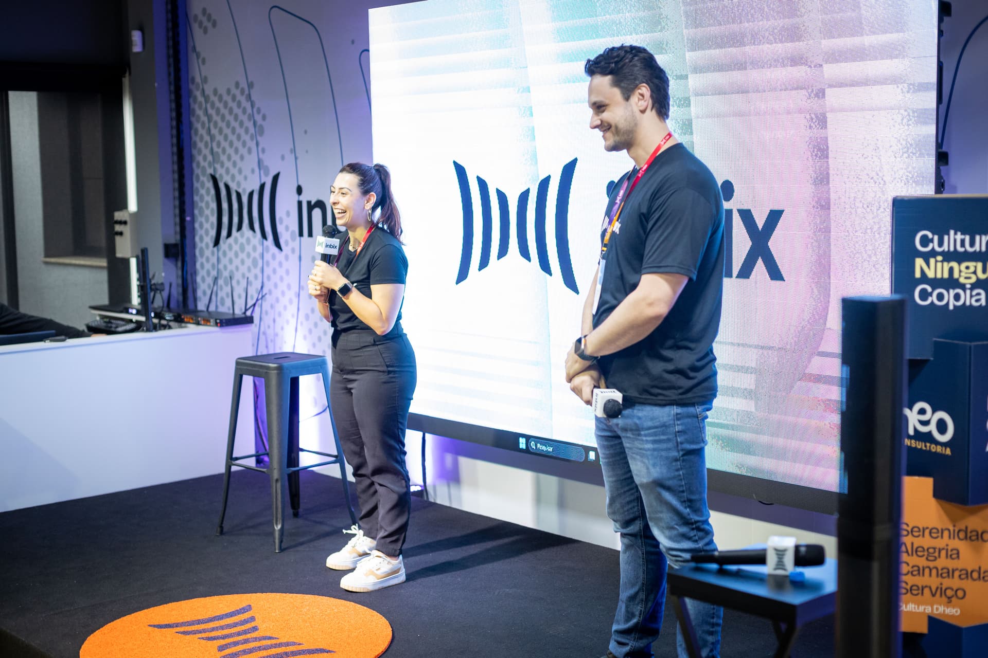 Dois palestrantes da Inbix apresentando no palco diante de um telão com a marca