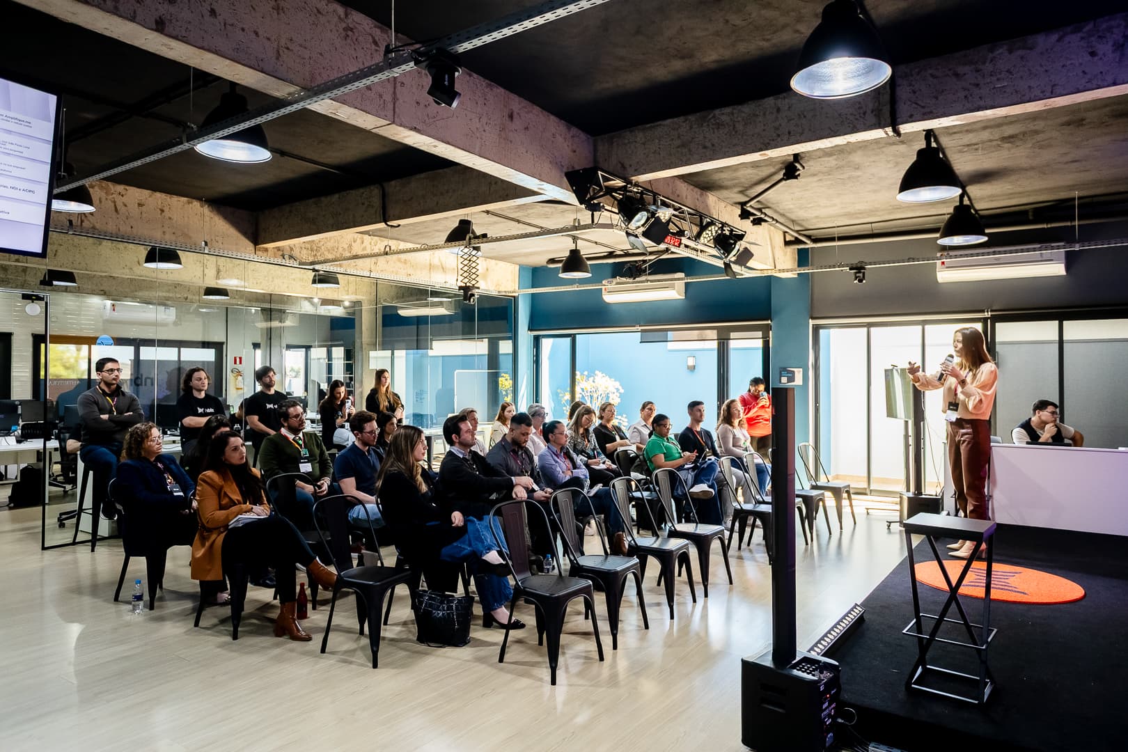 Público sentado acompanhando uma apresentação no espaço de eventos da Inbix