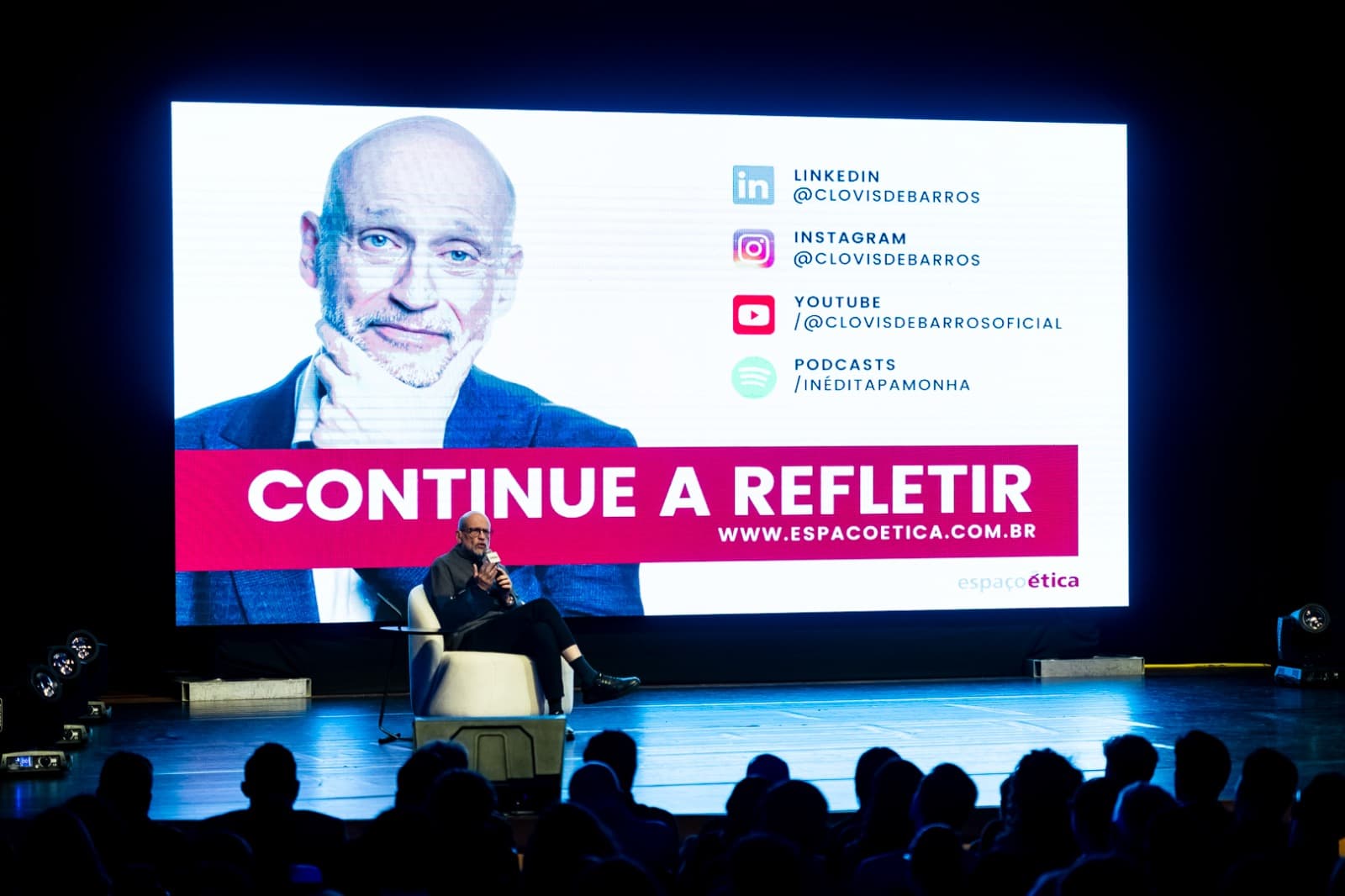 Palco com o telão da palestra de Clóvis de Barros Filho e o público sentado